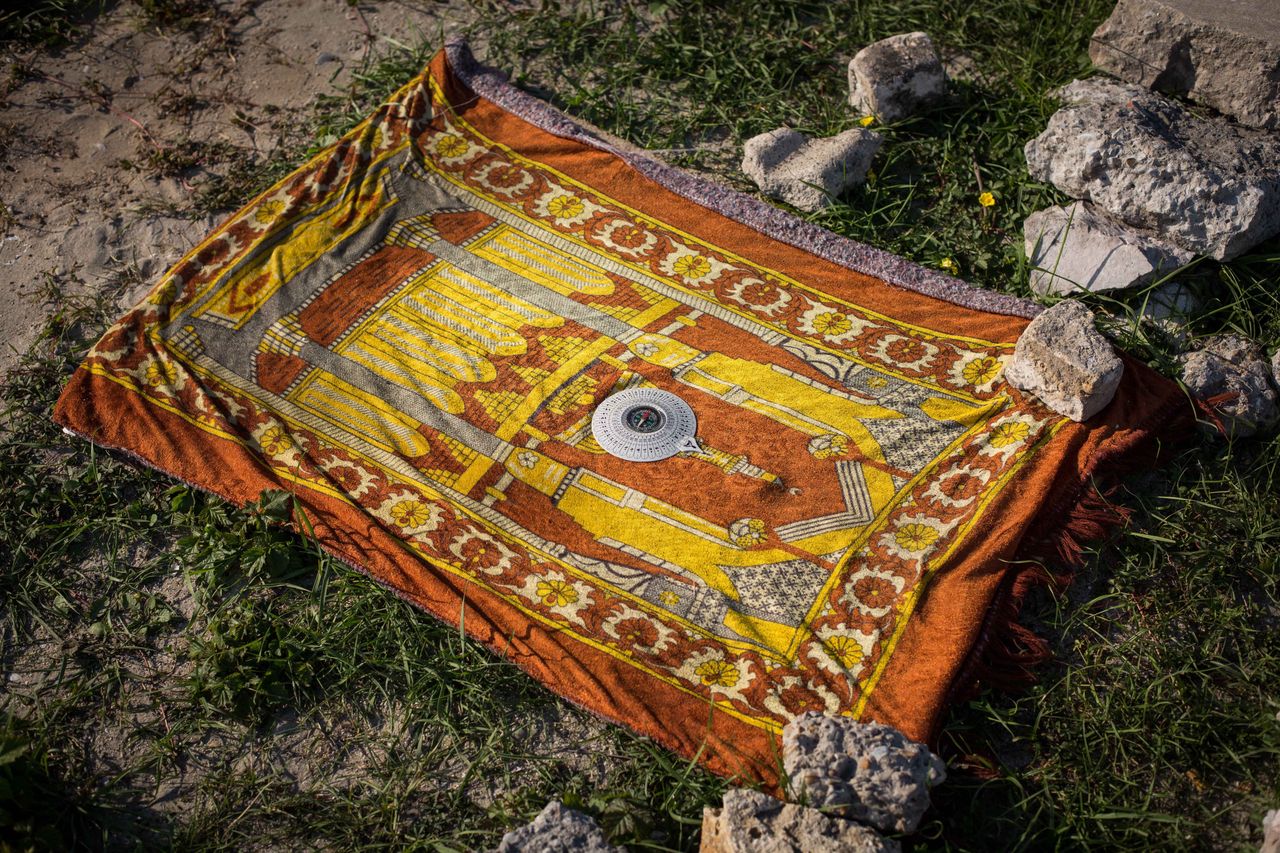 A compass rests on a prayer mat in a makeshift camp near the port of Calais on Aug. 2, 2015. 