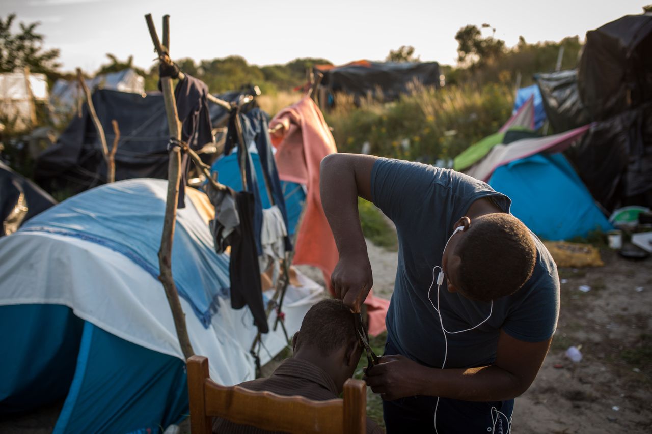 A man cuts another man's hair in a makeshift camp near the port of Calais on Aug. 2, 2015. 