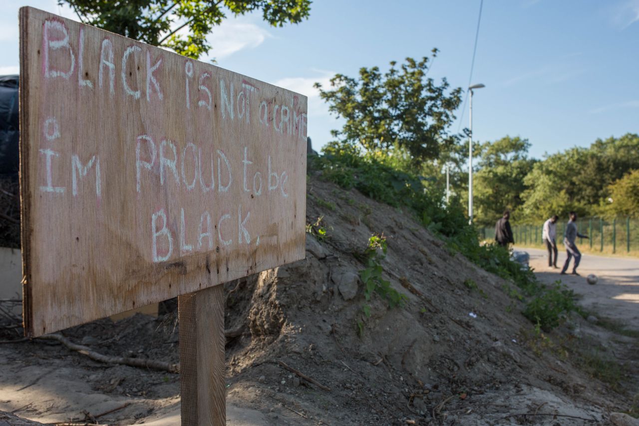A sign reading 'Black is not a crime, I'm proud to be black' is seen by the side of a track behind a makeshift camp near the port of Calais on Aug. 2, 2015. 