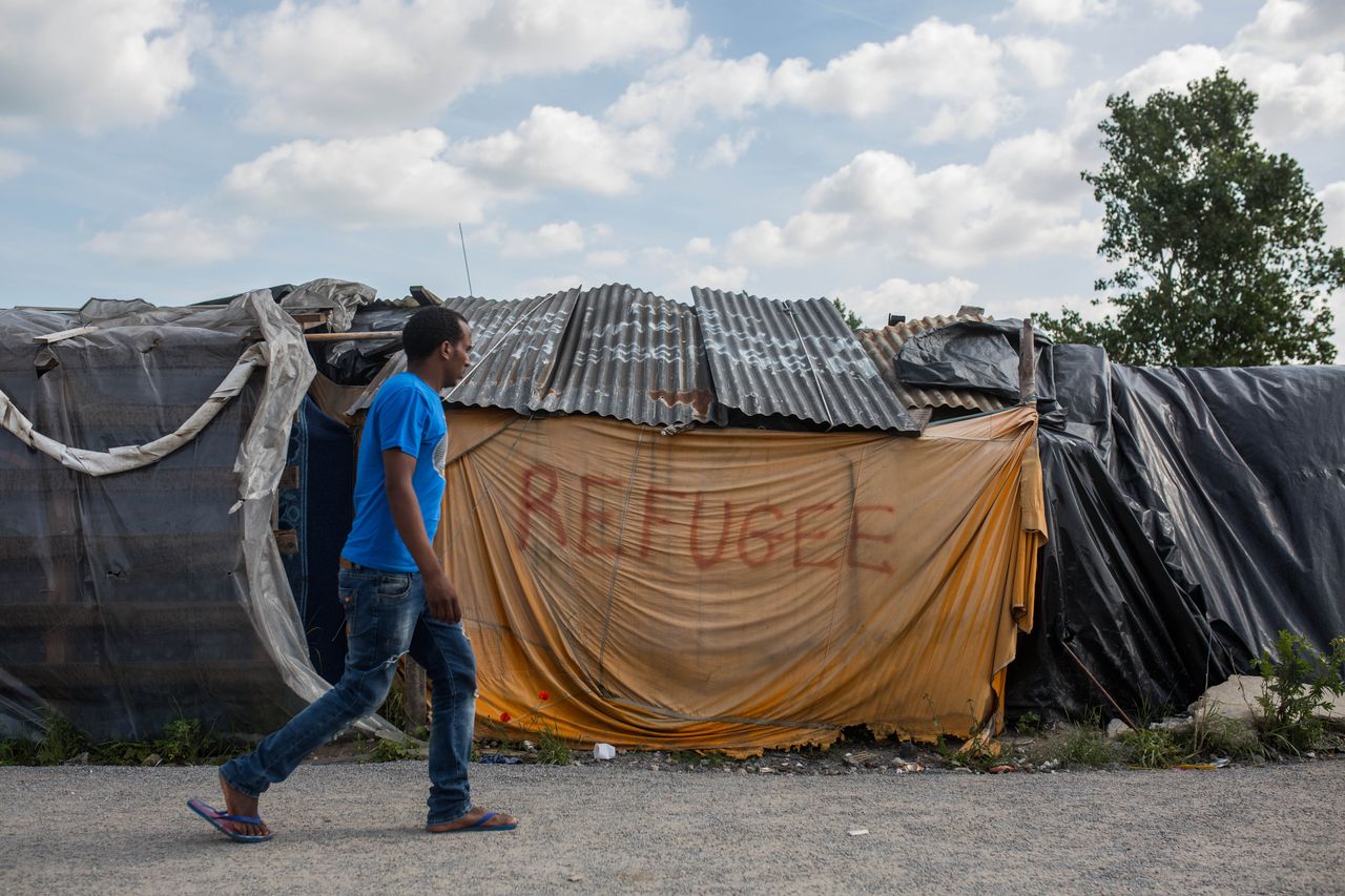 A man walks past a tent in a makeshift camp near the port of Calais on July 31, 2015.