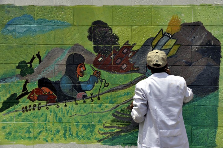 A Yemeni graffiti artist paints a mural protesting the airstrikes on the exterior wall of the Saudi Arabian Embassy in Sanaa,