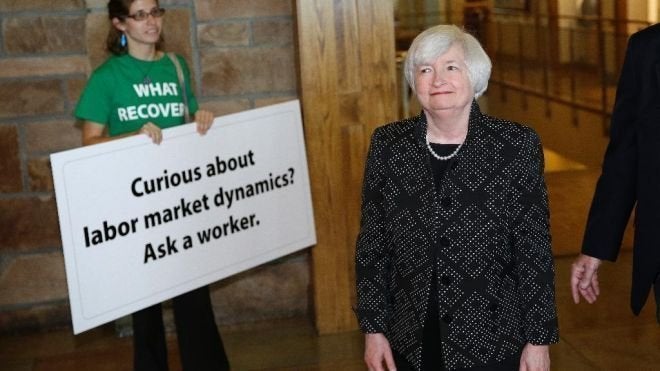 Fed Chair Janet Yellen looks on at a Fed Up activist drawing attention to workers at the Kansas City Fed's 2014 symposium in Jackson Hole, Wyoming.