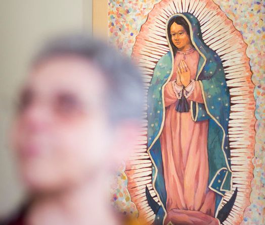 In front of a painting of Our Lady of Guadalupe, Sister Monica sits in her home. She has spent her career ministering to transgender people. 