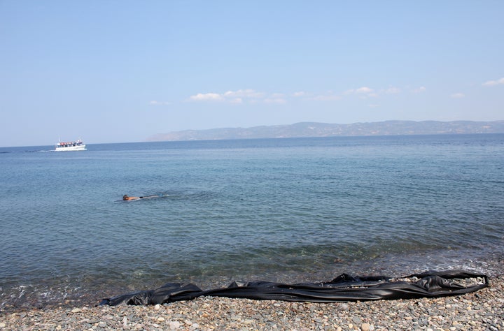 A tourist snorkels past a deflated rubber dinghy used by migrants to smuggle themselves from Turkey to the Greek island of Le