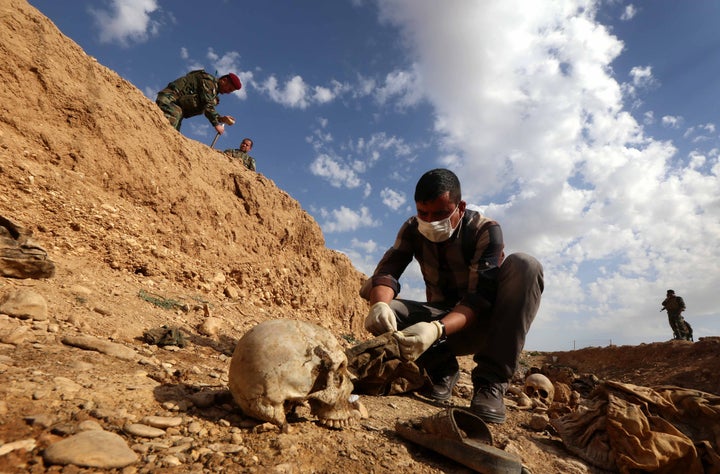 <p>An Iraqi man inspects the remains of members of the Yazidi minority killed by the Islamic State group after Kurdish forces discovered a mass grave near the village of Sinuni, in the northwestern Sinjar area, on Feb. 3, 2015.</p>
