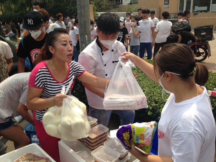 A volunteer hands out bread and chopsticks near the blast site on Friday afternoon.