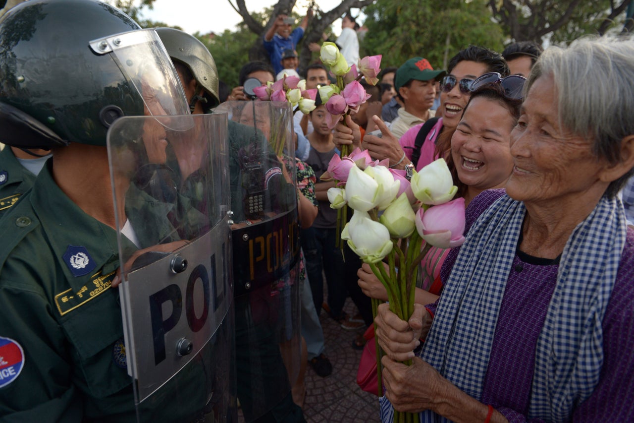 <p>Nget Khun holds lotus flowers in front of police officers during a 2013 protest against a land development project in Phnom Pehn. </p>