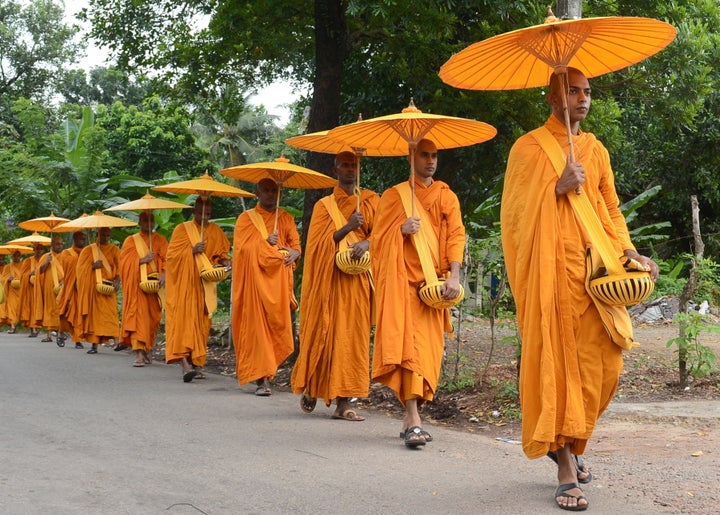 Sri Lankan Buddhist monks walk in line as they seek offerings of food in Colombo on July 25, 2015. 