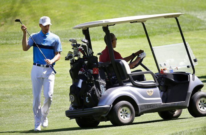 NBA basketball player Stephen Curry, left, returns a club to the cart as President Barack Obama, right, prepares to drive while golfing Friday, Aug. 14, 2015, at Farm Neck Golf Club, in Oak Bluffs, Mass., on the island of Martha's Vineyard. (AP Photo/Steven Senne)