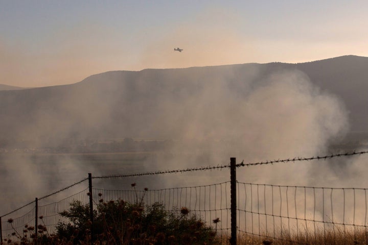 An Israeli firefighters plane flies over a field where rockets fired from Syria landed near Kfar Szold in northern Israel, close to the Golan Heights and the border with Lebanon, on Aug. 20, 2015.