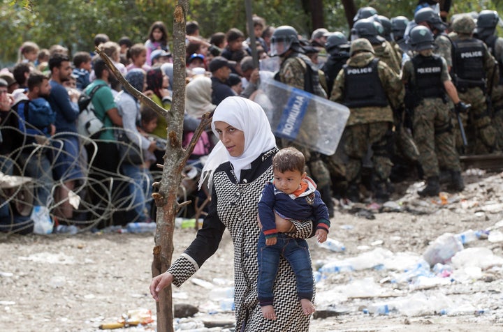 A woman carries a baby during a clash between Macedonian police forces and people trying to cross the border between Greece and Macedonia near the town of Gevgelija on Aug. 22, 2015. 