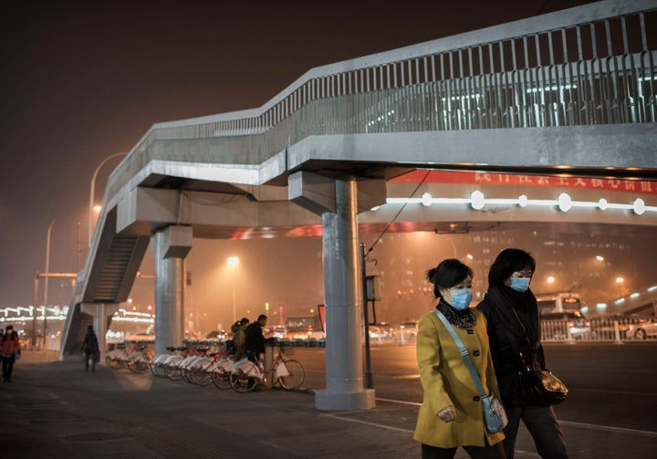 <span>Chinese women wear masks to protect against air pollution as they walk in the street in Beijing.</span>