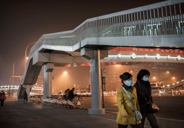 Chinese women wear masks to protect against air pollution as they walk in the street in Beijing.