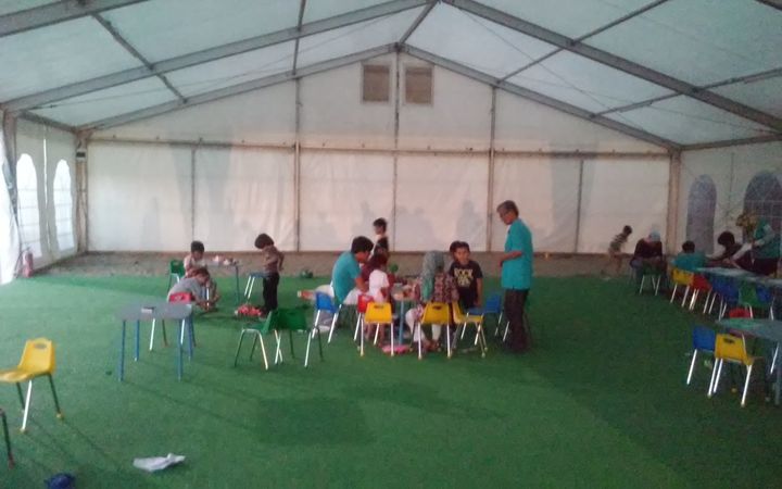 Several young children gather to play at the children's tent in the Eleonas camp. 