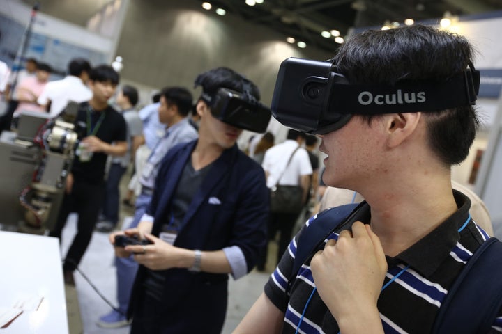 Attendees wearing the Oculus VR Inc. Rift headset play video games at the RoboUniverse Conference & Expo in Goyang, South Korea, on Wednesday, June 24, 2015.