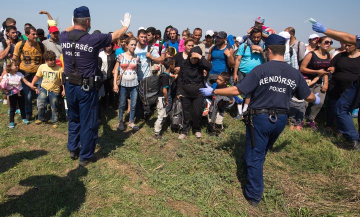 <p>Hungarian police officers control migrants who had just crossed the border from Serbia into Hungary near Szeged, Hungary, on Aug. 28, 2015.</p>