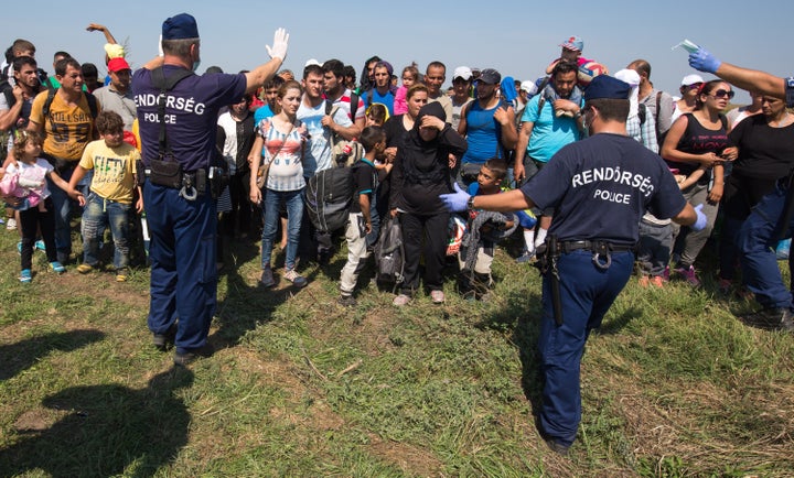 Hungarian police officers control migrants who had just crossed the border from Serbia into Hungary near Szeged, Hungary, on Aug. 28, 2015.