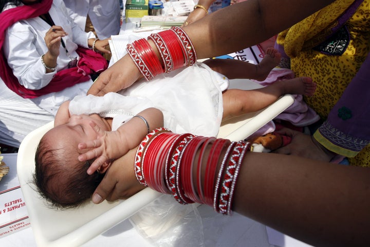 NEW DELHI, INDIA - APRIL 7: A mother places her infant on weighing machine during launch of Mission Indradhanush - an im