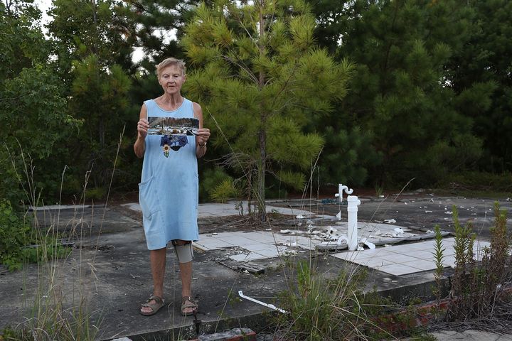 Linda McLain stands on the slab of her former home Waveland, Mississippi, holding a photo that was taken by her son 10 days after Hurricane Katrina destroyed the house. She decided not to rebuild on the site, but built a new home across the street. 