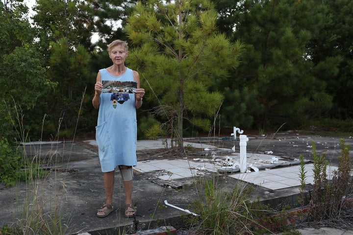 Linda McLain stands on the slab of her former home Waveland, Mississippi, holding a photo that was taken by her son 10 days a