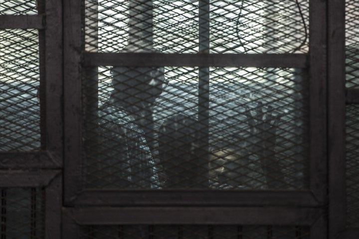 Al-Jazeera journalists, Canadian Mohamed Fahmy (R) and Egyptian Baher Mohamed (C), both accused of supporting the blacklisted Muslim Brotherhood in their coverage for the Qatari-owned broadcaster, sit in the defendants' cage during their trial in the capital Cairo on August 29, 2015. 