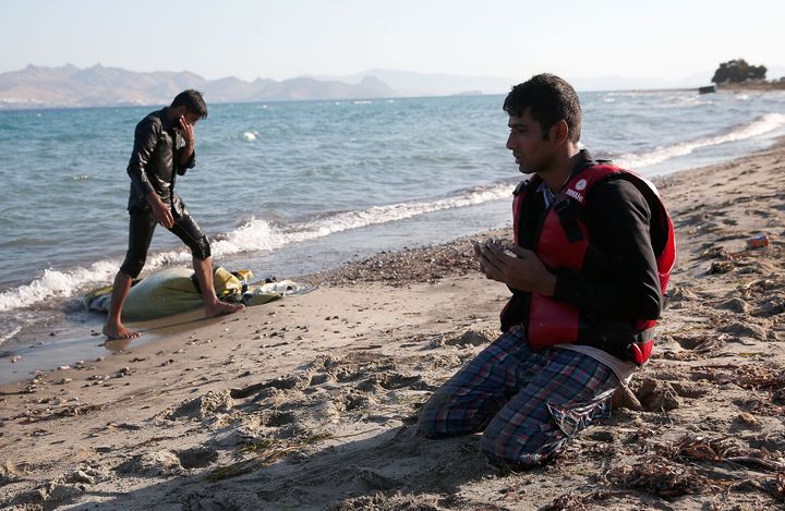A migrant from Pakistan prays on the beach after safely completing a journey across the Aegean Sea in a small boat from Turkey to Kos, Greece, on Aug. 29, 2015.