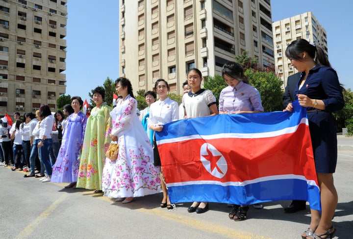 Young women hold a North Korean flag during a ceremony to name a park in Damascus after Kim Il Sung.