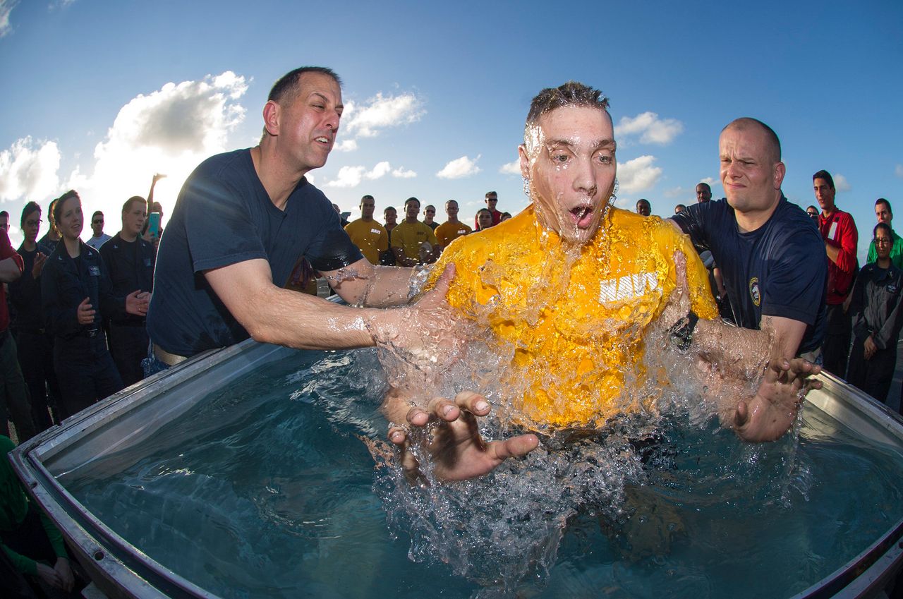 Lt. Cole Yoos, the command religious ministries department divisional officer aboard the Nimitz-class aircraft carrier USS George Washington (CVN 73), and Lt. Brian Kirschenbaum, a Carrier Air Wing (CVW) 5 chaplain, baptize Aviation Structural Mechanic (Safety Equipment) 2nd Class Ryan Norton, from Minto, North Dakota in the baptismal pool on the ship's flight deck during a baptism-at-sea. 