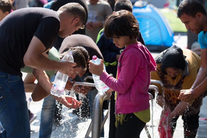 Access to sanitation, food and water is extremely limited. Here, a child fills up a water bottle while those around her attempt to clean up.