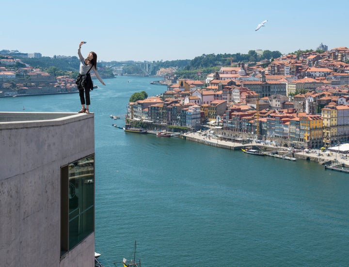 Woman shooting dangerous selfie with city view. 