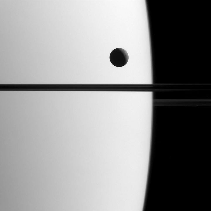 A view of one of Saturn's moons, Dione, passing the planet.