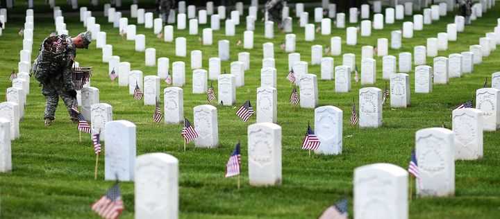 A soldier places flags at gravesites during a Memorial Day ceremony at Arlington National Cemetery in Virginia, May 22, 2014.