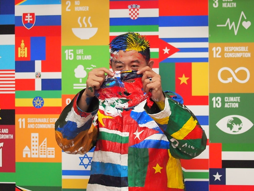 Liu peels a mask of paint from his face after an assistant snaps a photo of his work.