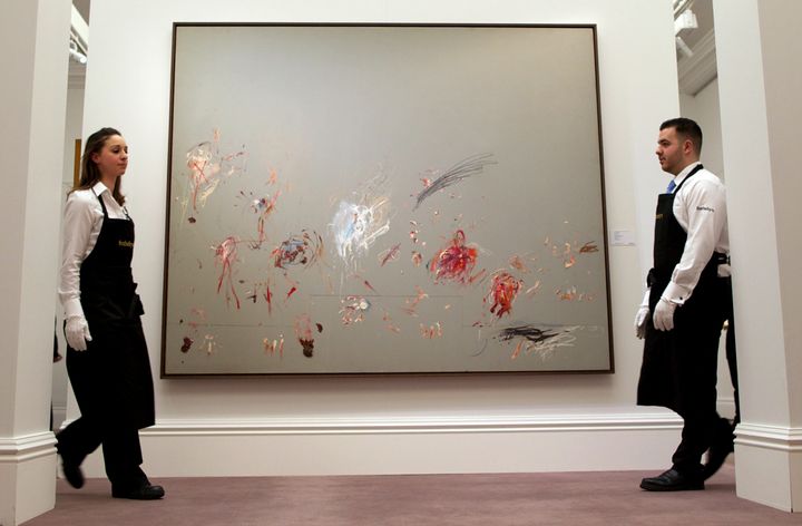 Sotheby's employees walk past a newly-discovered painting by Cy Twombly during the Sotheby's Impressionist, Modern & Contemporary Art auctions press preview in London on January 29, 2014. (ANDREW COWIE/AFP/Getty Images)