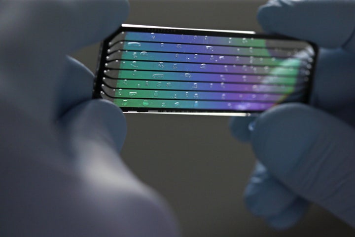 A senior research technician, holds up a used flow cell to display its intricacies at the Genome Institute at Washington University.