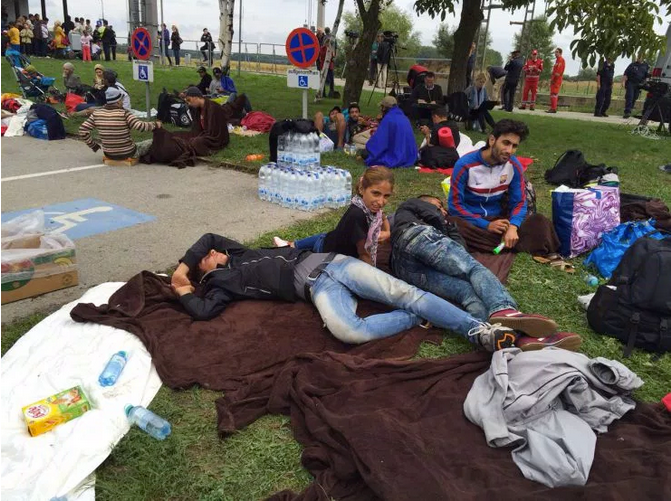 Weary travelers collapse on the grass outside Nickelsdorf train station in Austria.
