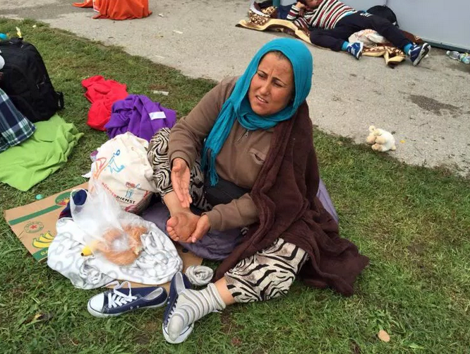 Syrian woman rubs her blistered feet at Austrian train station.
