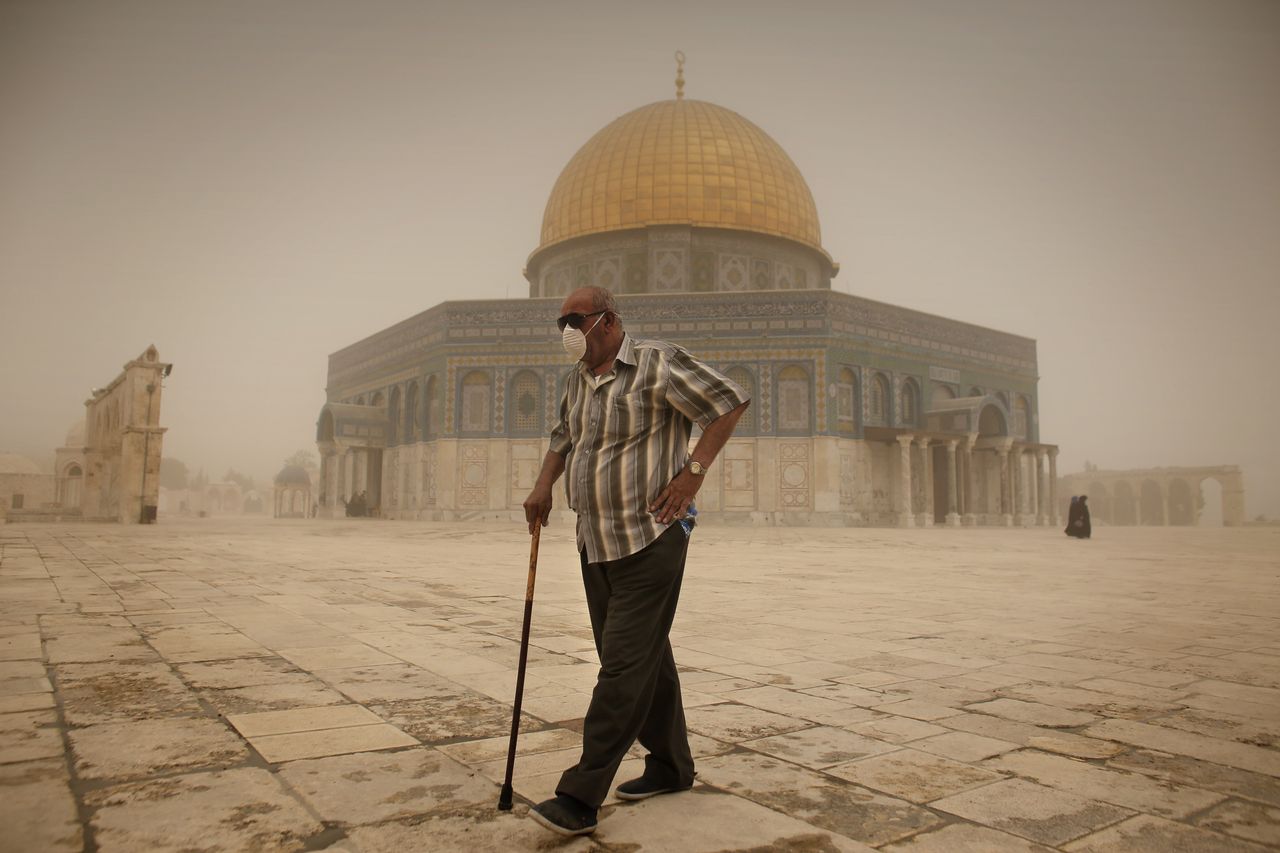 A Palestinian man wears a mask to protect his face from the dust as he walks past the Dome of the Rock mosque in the al-Aqsa Mosque compound in Jerusalem, on Sept. 8, 2015.