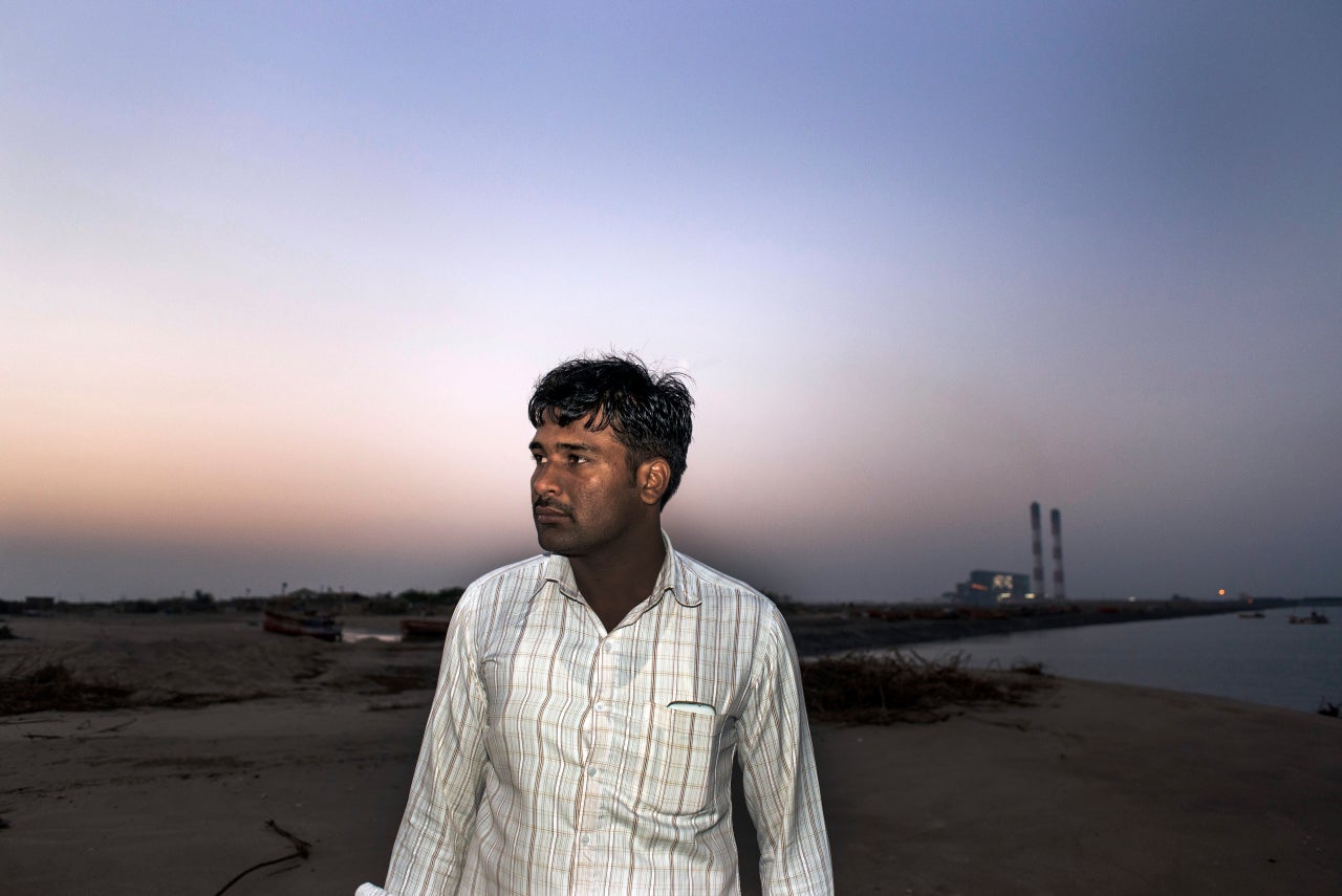 Gajendrasinh Jadeja, an elected village chief in western India, stands in front of a coal-burning power plant financed by the World Bank Group. Jadeja claims local police have repeatedly detained him in an effort to squelch his criticism of the coal plant and other industrial projects.