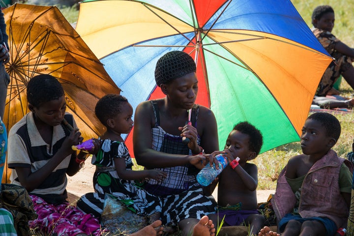 A family of Burundian refugees rests in the shade of their umbrellas at the Lake Tanganyika Stadium in Kigoma, on May 20, 2015. There has been an outbreak of cholera and acute diarrhea among the refugees fleeing Burundi. 