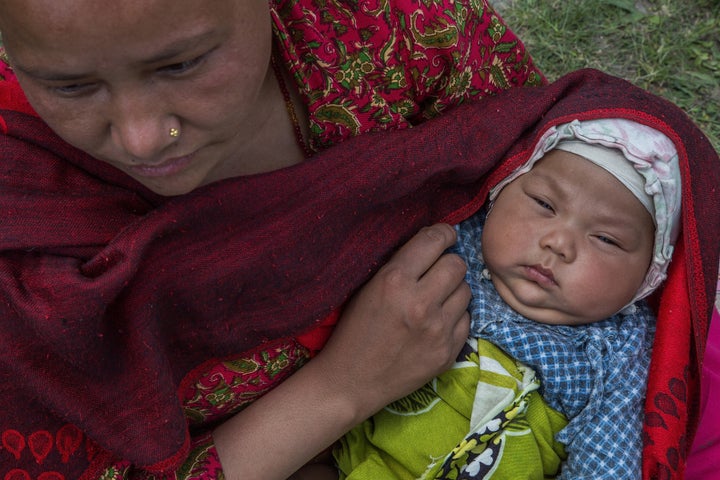 <span> A mother holds her child in an evacuation area set up by the authorities in Tundhikel park on April 27, 2015 in K