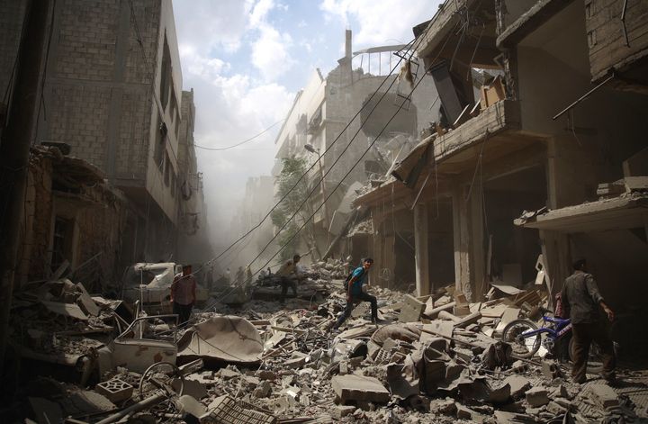 <p>Syrians walk through the rubble caused by an alleged government airstrike in Douma, Syria.</p>