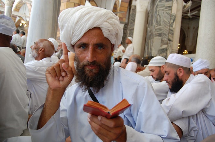 An Afghan “Hajji” (pilgrim) raises his index finger to denote a central precept of Islam, while holding a Quran in the other hand, during a scene from Parvez Sharma’s film “A Sinner in Mecca.” 