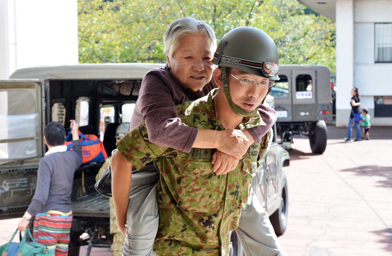 A soldier carried an elderly woman to a shelter in Tsukubamirai, Ibaraki prefecture, on Friday after an embankment of the Kinugawa river collapsed.