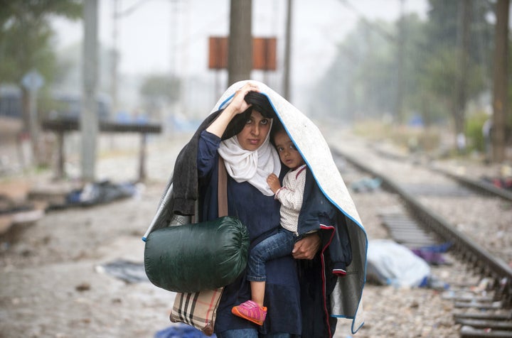 A migrant woman holds her child as they cross the border between Greece and Macedonia near the town of Gevgelija on Sept. 10,
