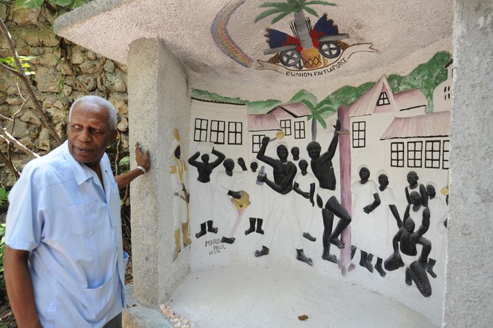 Haitian voodoo leader Max Beauvoir shows a relief painting of a voodoo ceremony in a 2010 file photo.