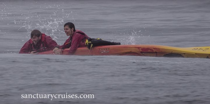 Two kayakers are seen smiling after nearly being crushed by a humpback whale. 