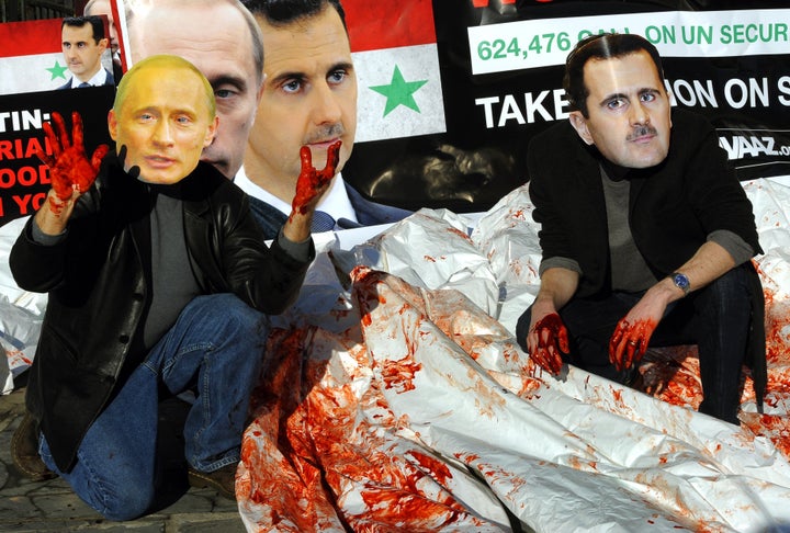 Activists wearing giant masks of Syrian president Bashar Assad and Russian president Vladimir Putin dump bloodied body bags outside the United Nations Security Council building on Jan. 24, 2012, as members of the UN Security Council meet in New York to discuss the Syria crisis.