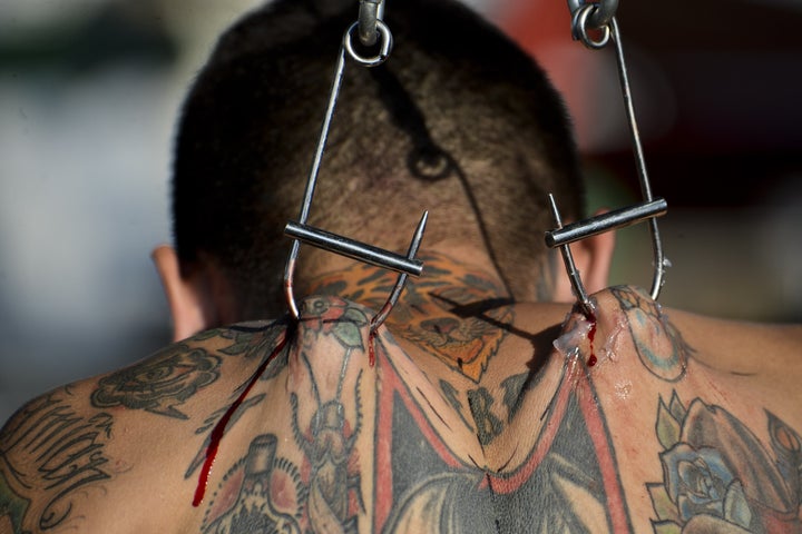 Body modification artist Damian Carnicero was suspended in the air with metal hooks attached to his back at the 2015 Cali Tattoo Festival in Cali, Colombia.