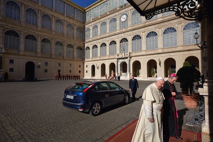 Pope Francis talks with the prefect of the papal household, Archbishop Georg Gänswein. The pontiff’s blue Ford Focus is visible behind him.